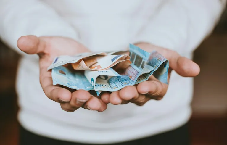 Open hands holding out a bundle of banknotes