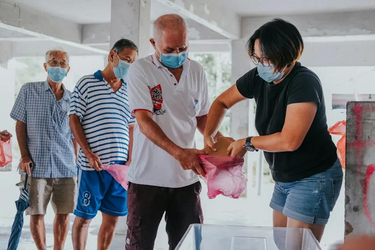 A volunteer handing out food parcels to people waiting in line